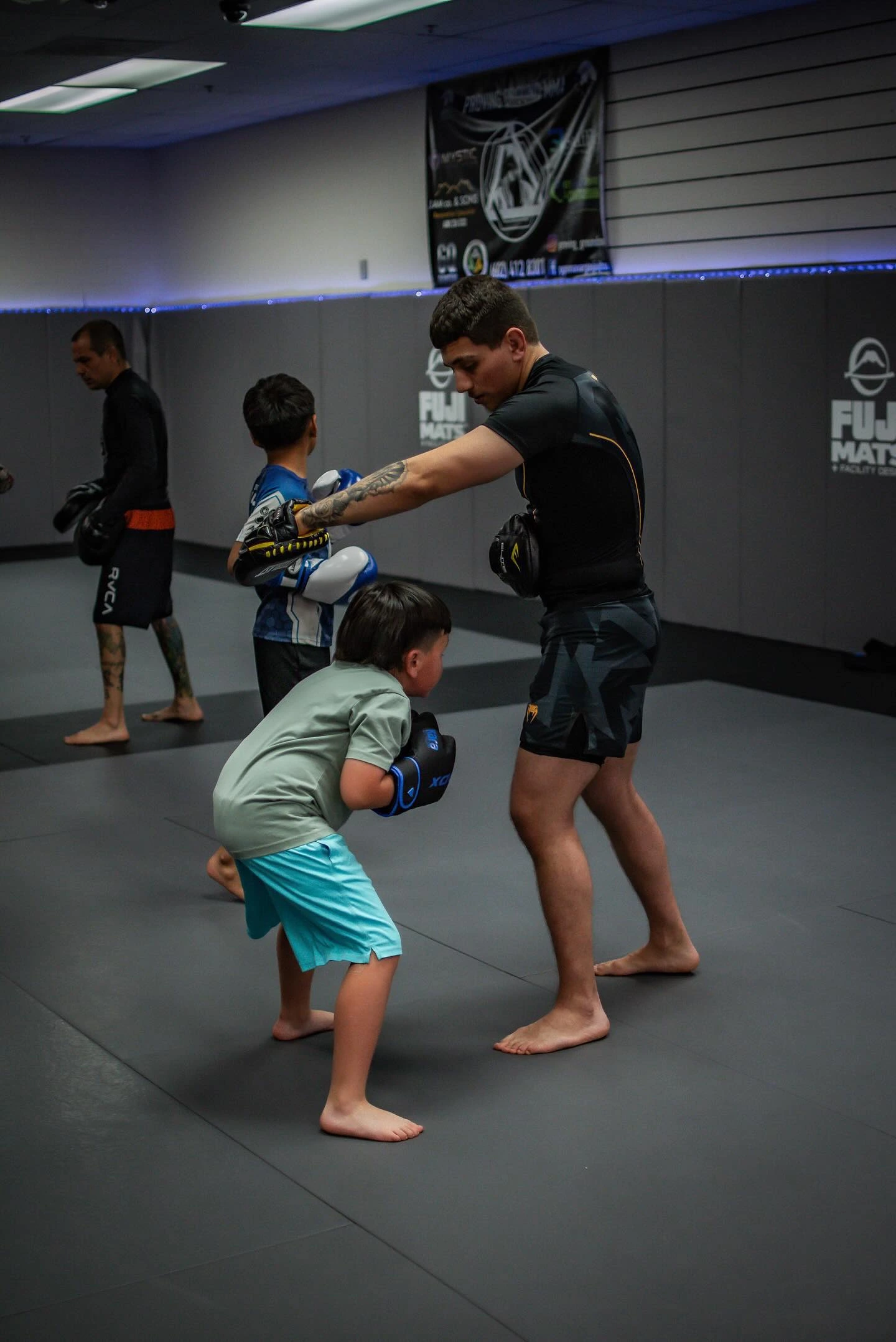 Coach training young kids with boxing mitts